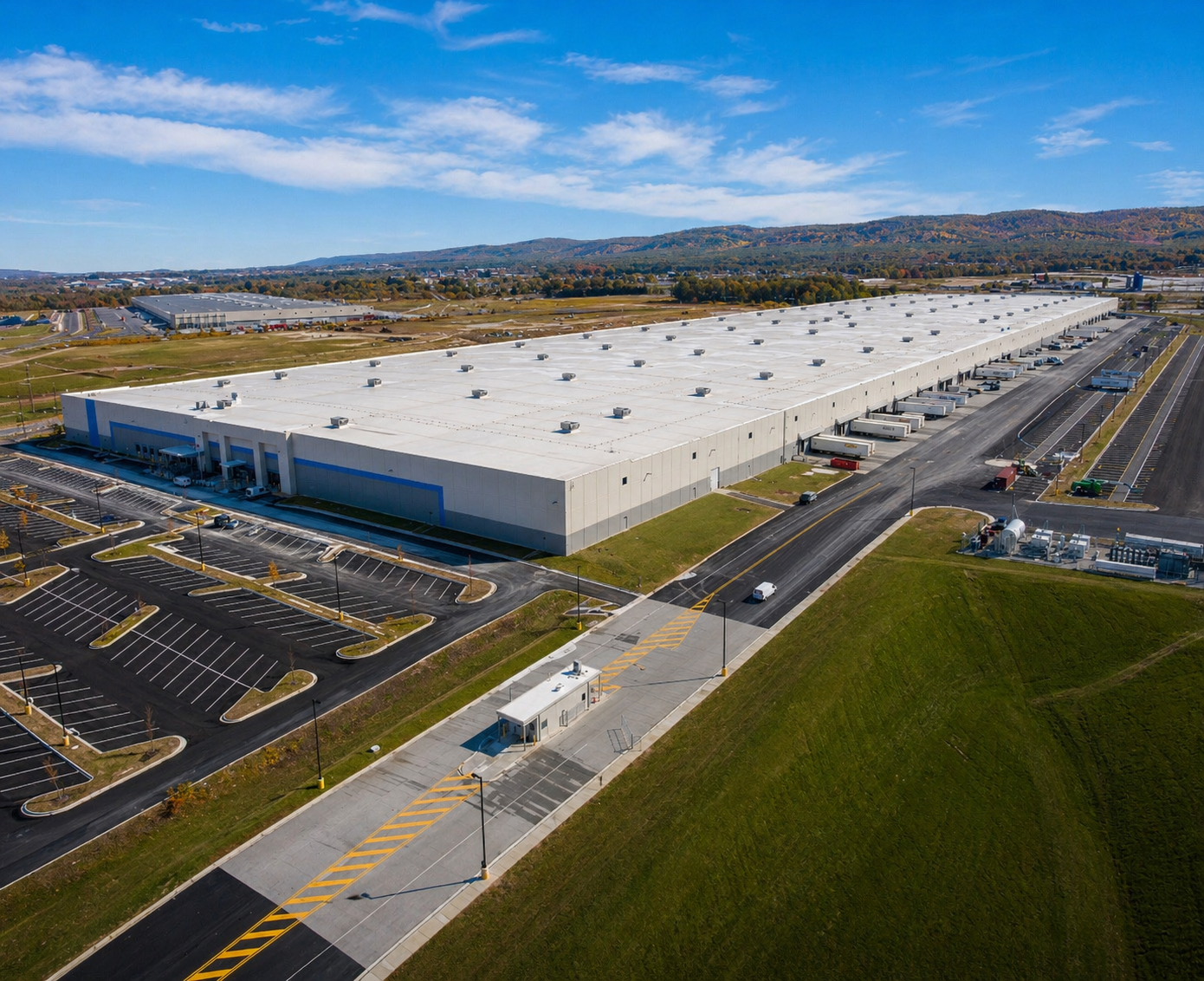 Aerial view of a large white industrial warehouse with loading docks trailers and surrounding parking lots