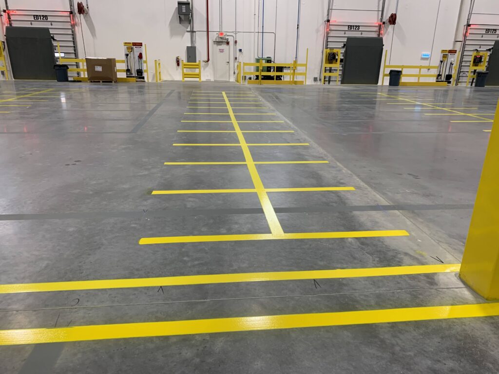Industrial warehouse striping project with yellow safety lines and traffic flow markings