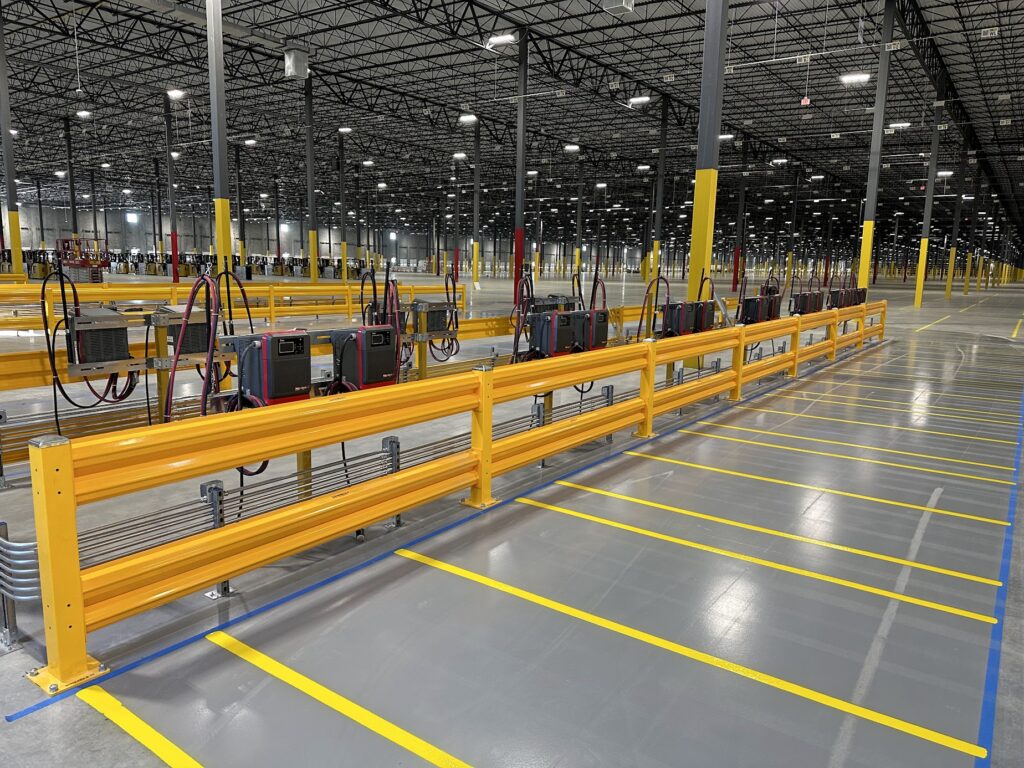 Wide view of a modern warehouse with yellow safety rails and electrical equipment along an assembly line in Phoenix AZ