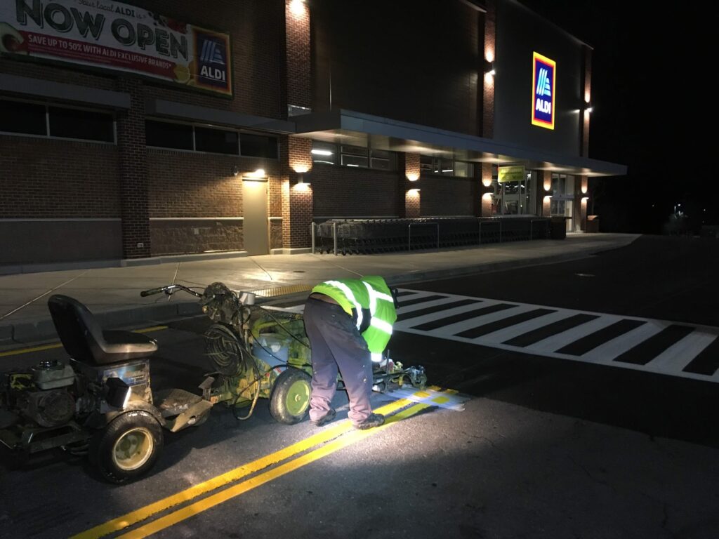 Universal Striping crew painting parking lot lines outside ALDI at night