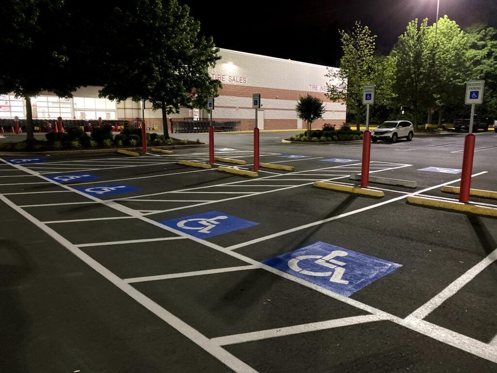 Nighttime commercial parking lot with white stall lines and blue accessible parking symbols