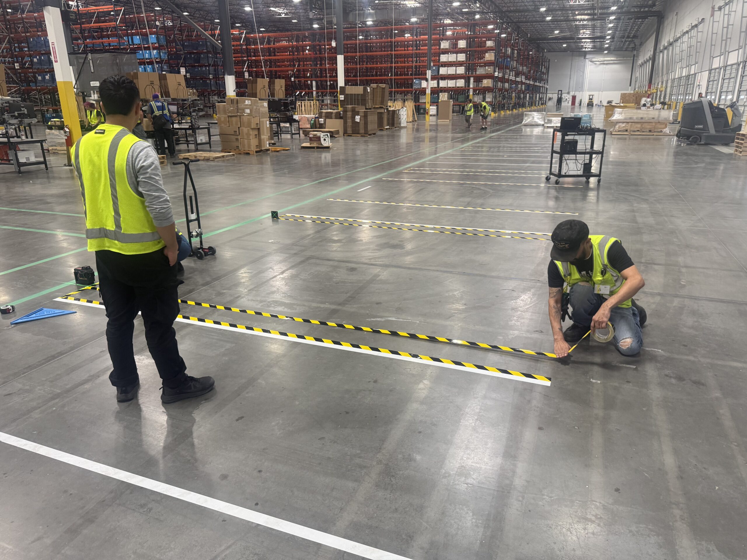 Black and yellow hazard floor tape installed in active warehouse