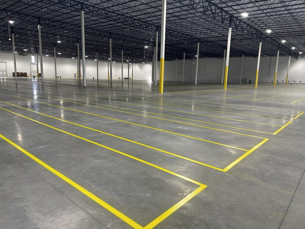 Large distribution warehouse with professional yellow epoxy floor striping and marked storage lanes