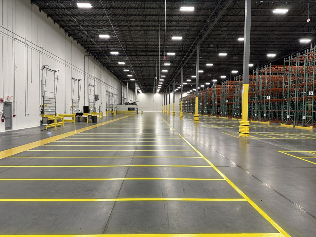Yellow warehouse loading lanes beside dock doors and pallet racks