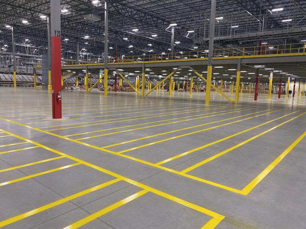 Yellow warehouse staging lines below an industrial mezzanine