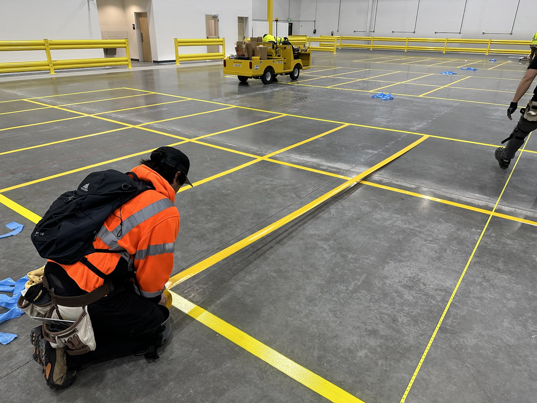 Warehouse technician installing yellow floor marking tape
